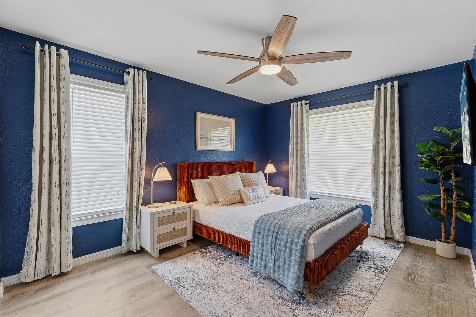 Guest bedroom with navy walls and orange velvet bed
