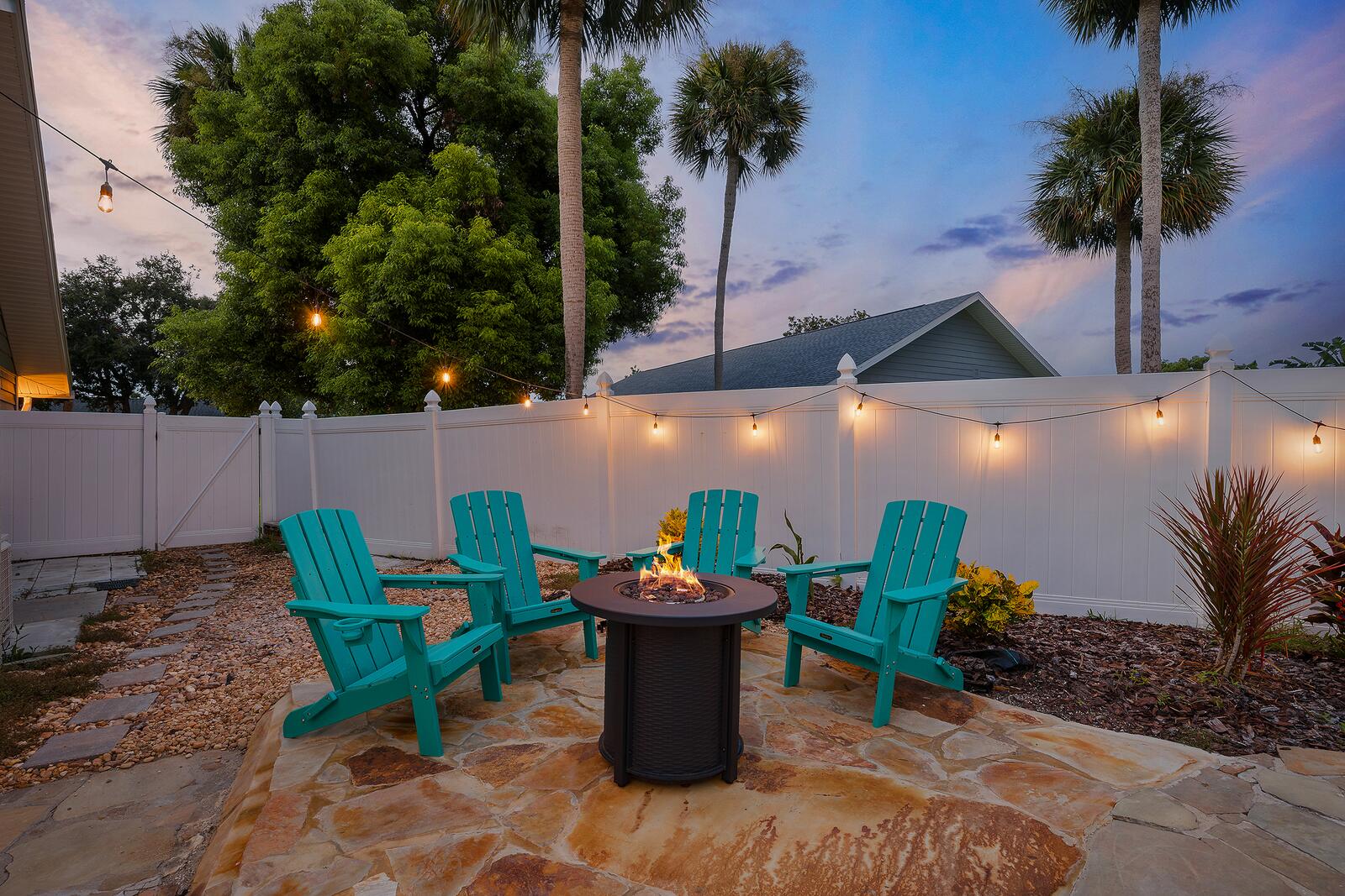 Fire pit with Adirondack chairs under string lights