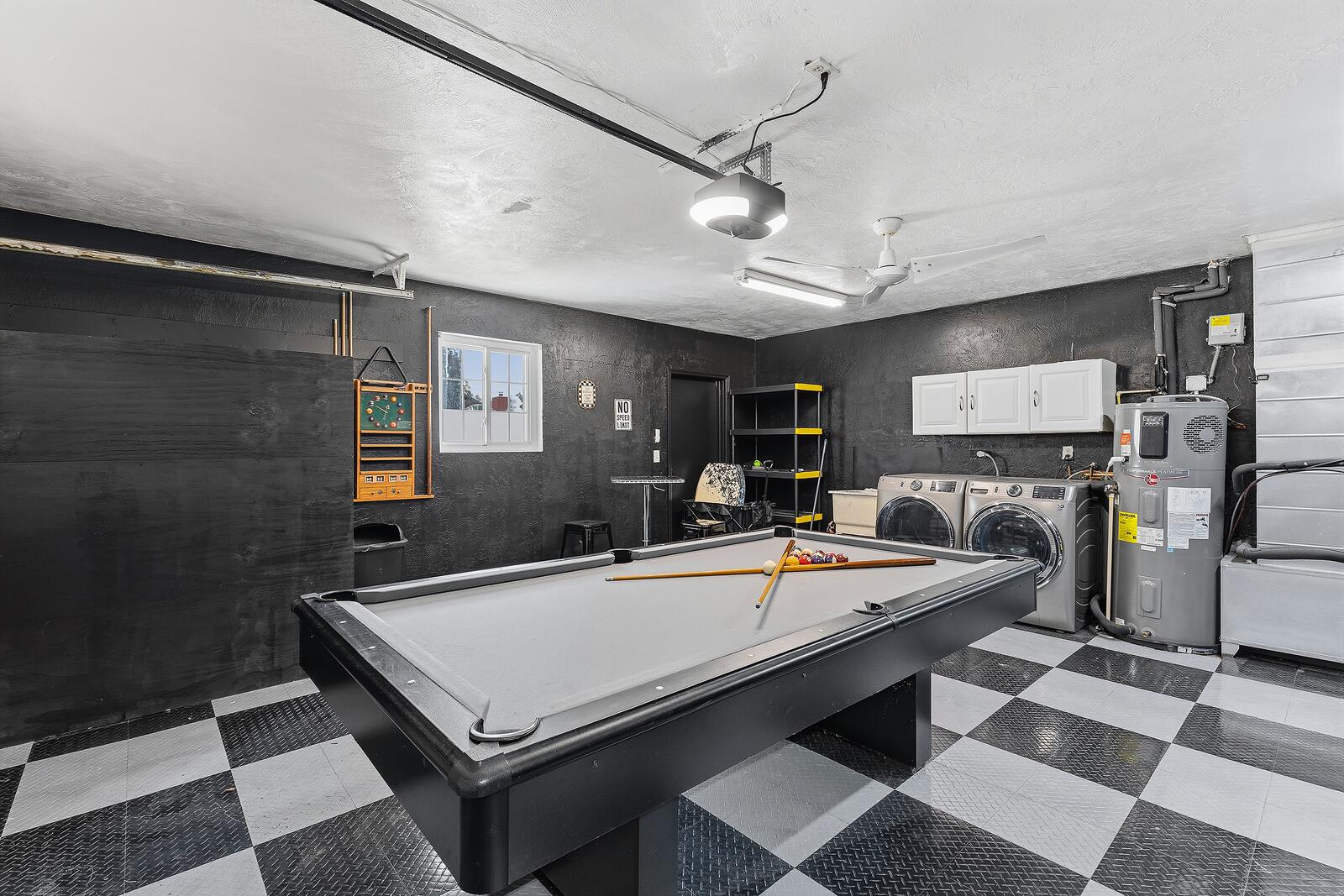 Racing-themed garage game room with checkerboard floor, pool table, and arcade games