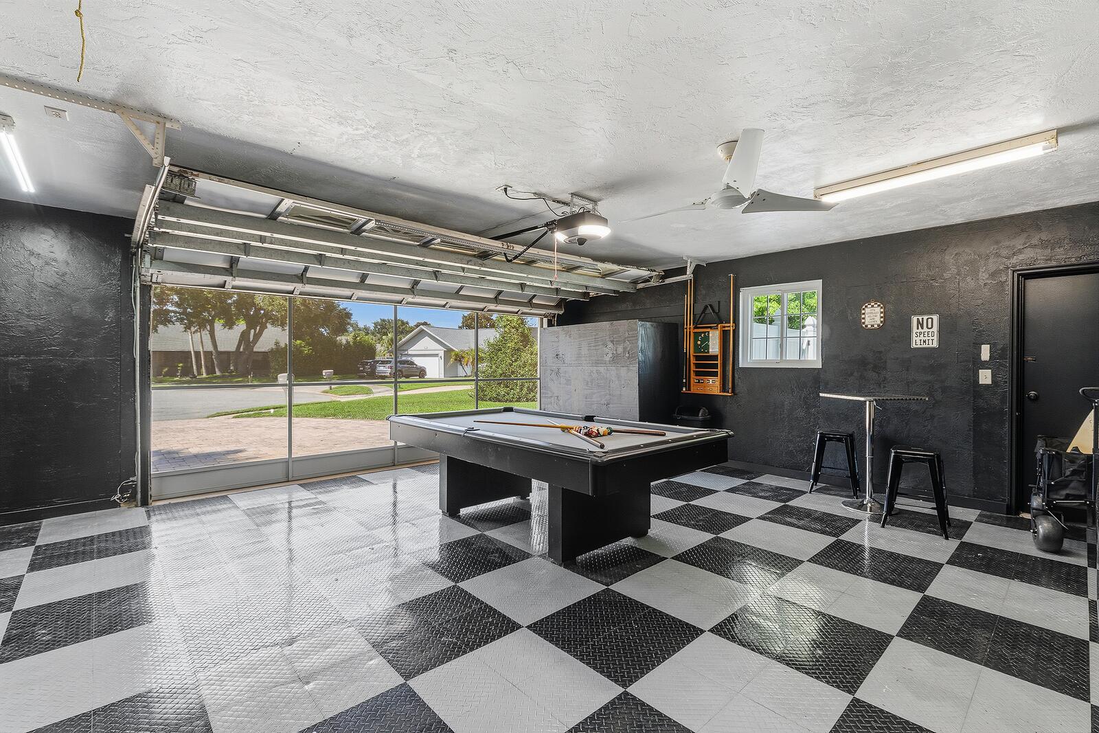 Garage game room with checkerboard floor, pool table, and screened bay door