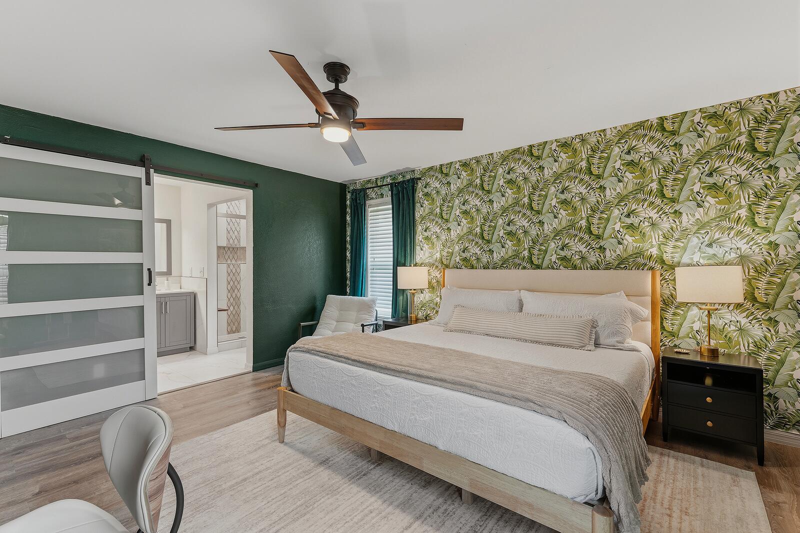 Primary bedroom with king bed and tropical leaf accent wall