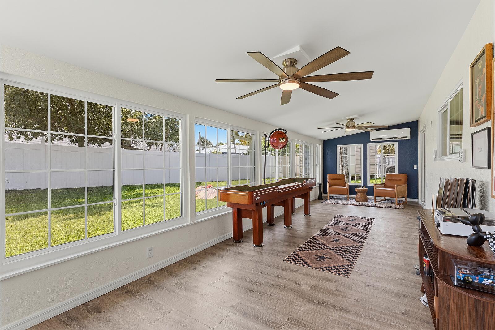 Air-conditioned sunroom with shuffleboard table overlooking the pool